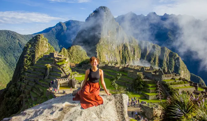 Heather, een vrouwelijke soloreiziger, poseert in Machu Picchu in Peru