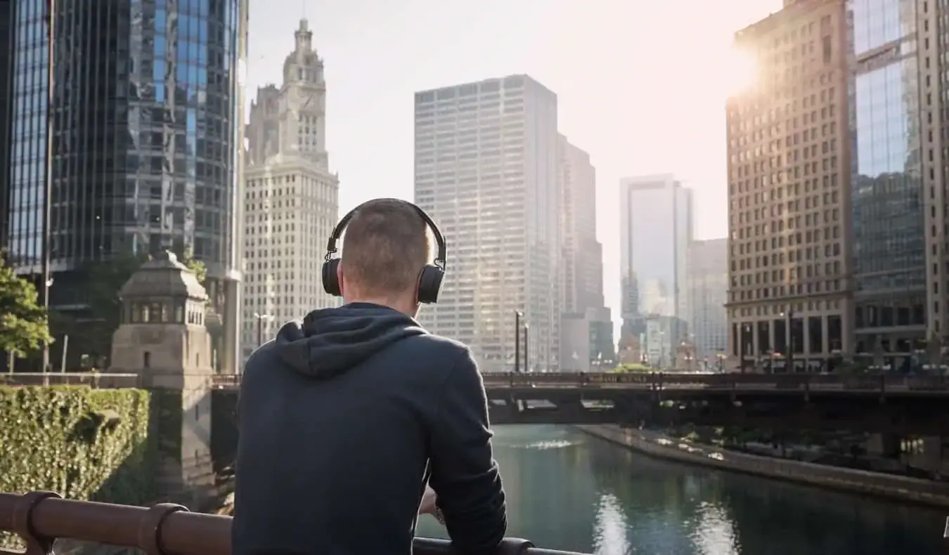 Lelaki memakai sepasang fon kepala atas telinga sambil melihat ke latar langit Chicago