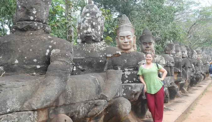 Una viajera solitaria posando cerca de estatuas religiosas mientras recorre el mundo