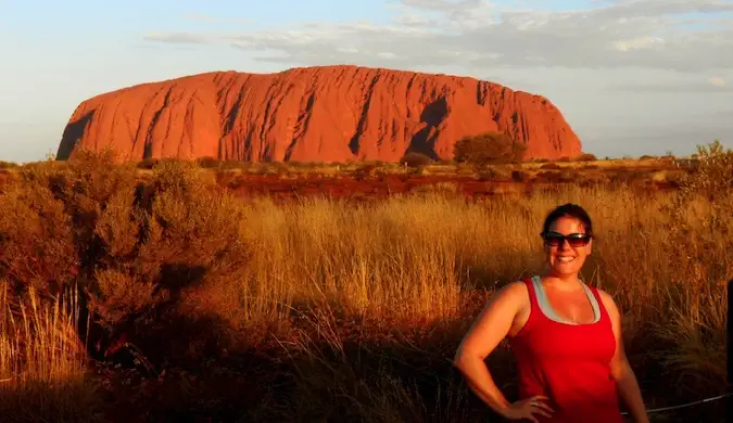 En kvinnelig alenereisende poserer nær Uluru i Australia