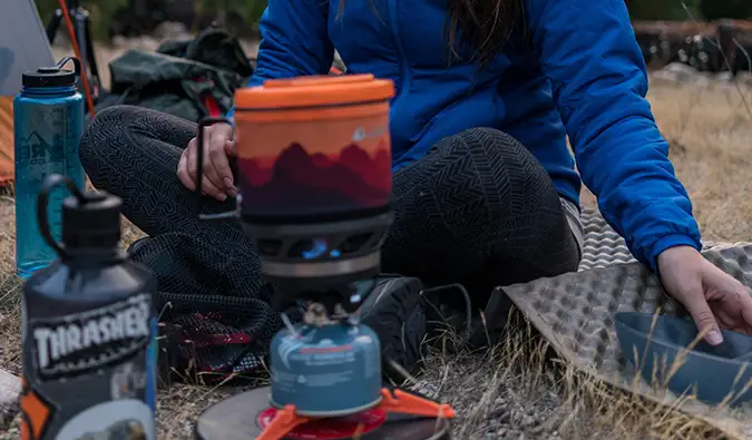 uma mulher montando uma fogueira enquanto acampava