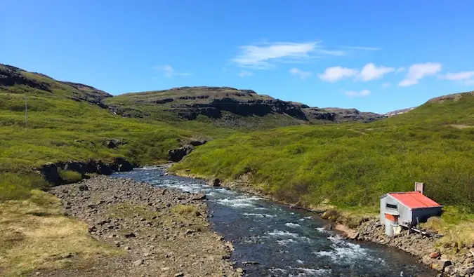 Sebuah pondok kecil di sebelah sungai cetek di Westfjords, Iceland