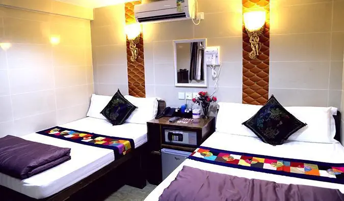 Dua tempat tidur ganda dengan kulkas mini di antaranya dalam sebuah kamar di Australia Guesthouse di kompleks Chungking Mansions di Hong Kong