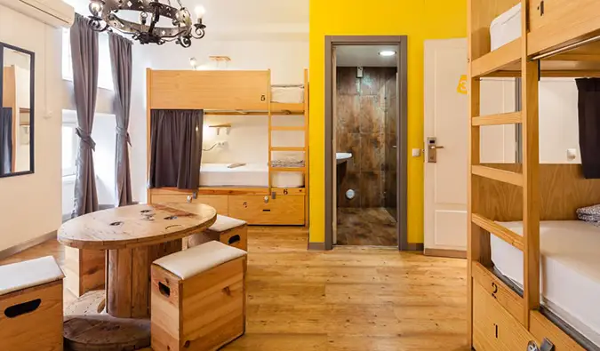 Dormitorio con literas de madera y pequeña mesa redonda en Yes! Hostal Lisboa