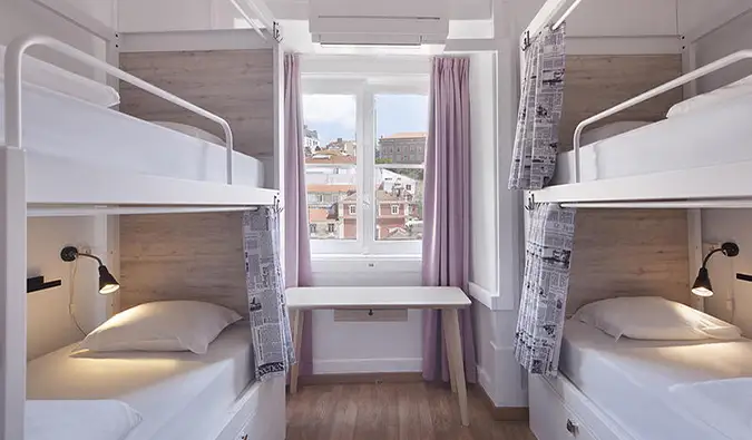 Dormitorio moderno con literas y ventana con vistas a los tejados de Lisboa en Good Morning Solo Traveler Hostel, Lisboa