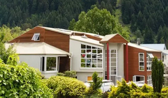 Außenansicht der hölzernen, modern aussehenden Haka Lodge vor einem Wald in Neuseeland