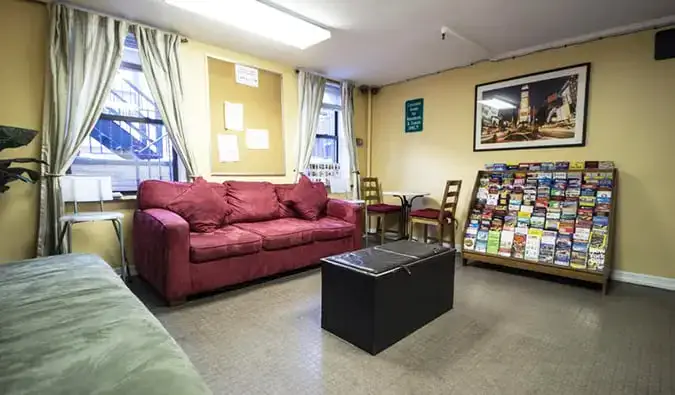 Kawasan umum asas dengan sofa dan rak risalah di Chelsea Hostel di NYC