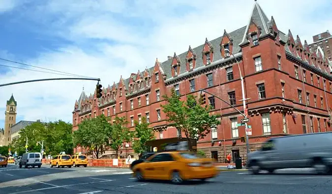 Bangunan bata besar dengan taksi kuning lewat di HI New York di NYC