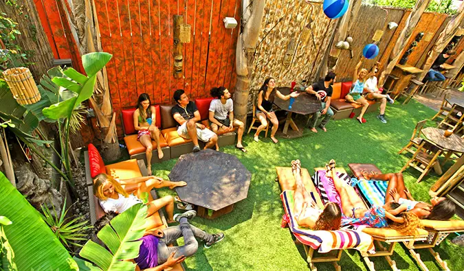 Maraming tao ang tumatambay at namamahinga sa mga outdoor couch at lawn chair sa Banana Bungalow Hollywood sa Los Angeles