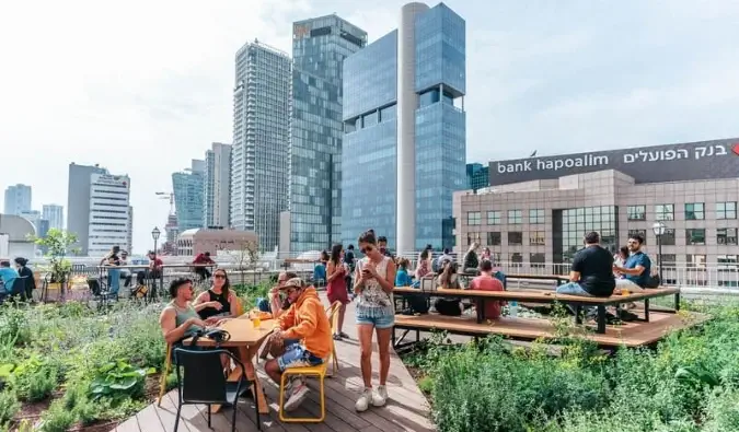 Mga taong tumatambay sa rooftop hostel ng Abraham Tel Aviv hostel, na may mga skyscraper sa background, sa Tel Aviv, Israel