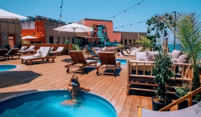 Femeie relaxată în piscina de pe acoperișul hostelului Selina din Tel Aviv, Israel