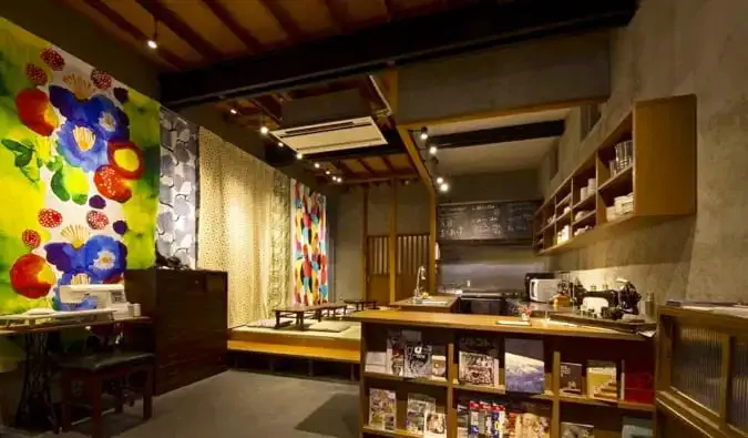 Sala común con recepción, estanterías y asientos de diseño tradicional japonés en el albergue Sheena and Ippei en Tokio, Japón