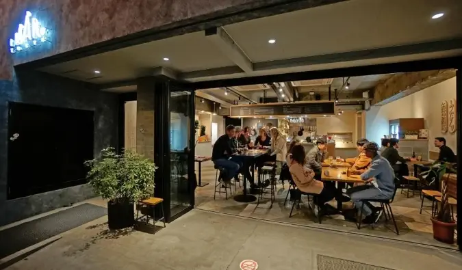 Mensen zitten en praten in de bar, gezien door de kamerhoge ramen van het Imano Tokyo Hostel in Tokio, Japan