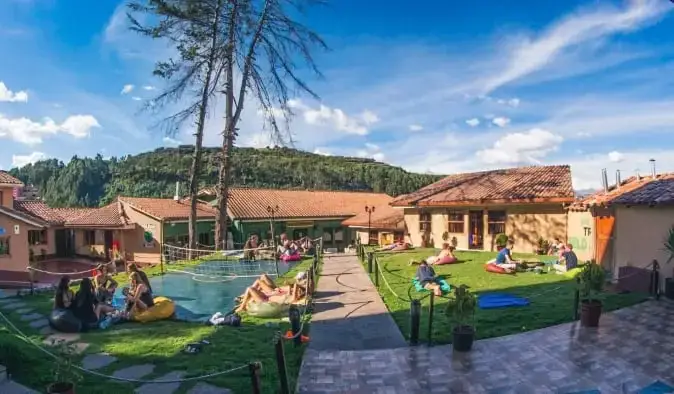 Uitgestrekte tuin met mensen die tuinspelletjes spelen en loungen in Wild Rover, een hostel in Cusco, Peru