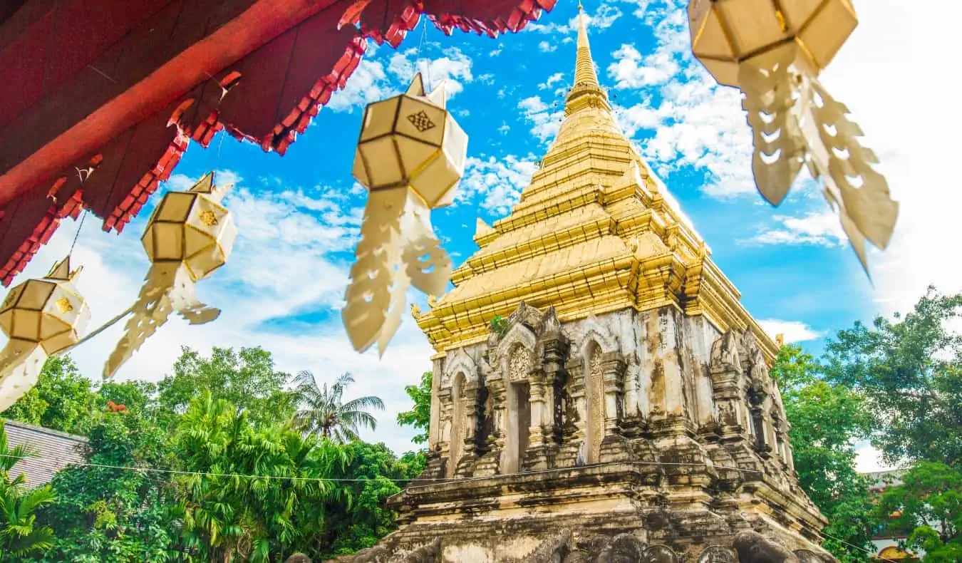 Buddhistisk tempel med flag, der flyver mod en solrig himmel i Chiang Mai, Thailand