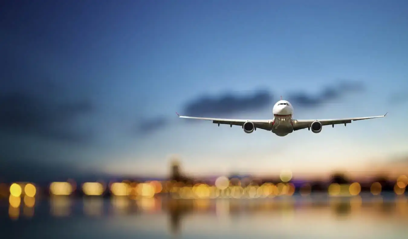 Un enorme avión comercial volando a través del cielo azul oscuro mientras aterriza en un aeropuerto