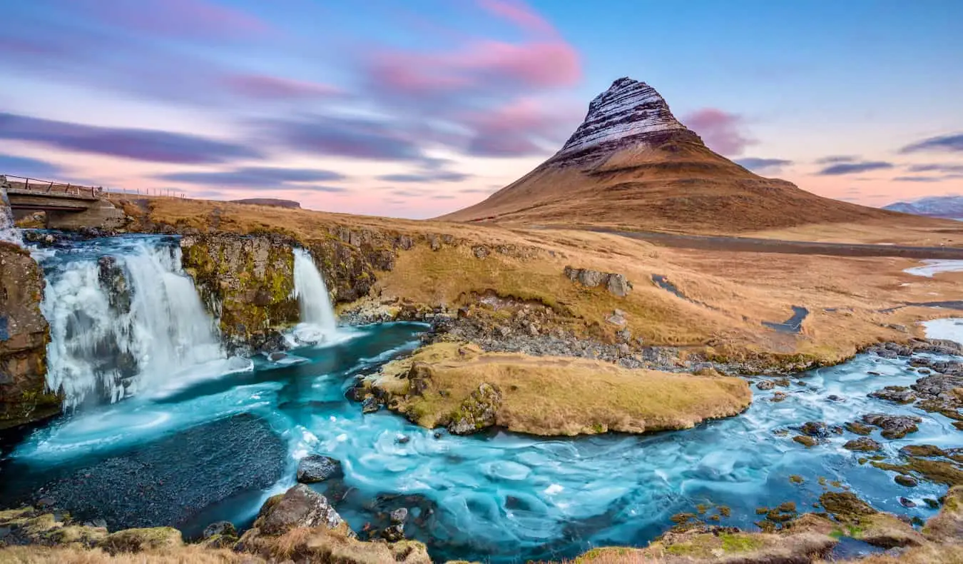 A híres Kirkjufell-hegy Izlandon naplementekor magasan a zord tájak között