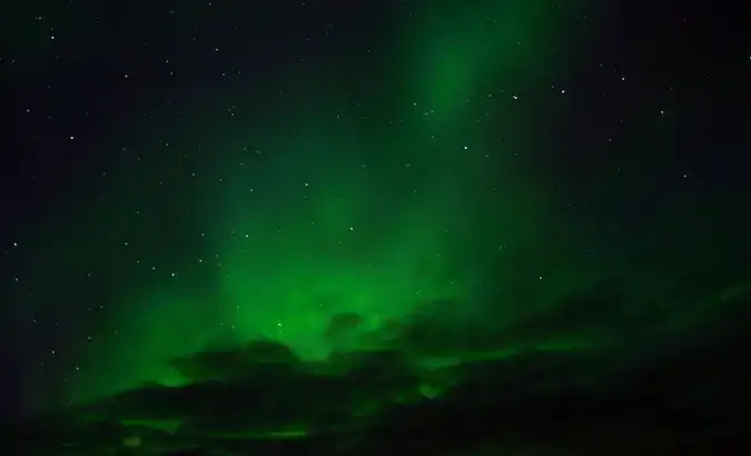 Aurora boreală luminând cerul în verde