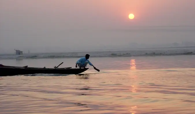 Seorang pria duduk di tepi perahu kayu kecil