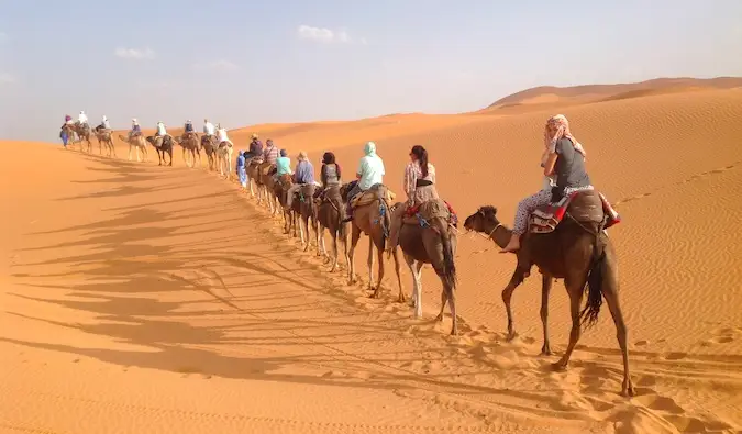 Nomadic Matt dando un paseo en camello por el desierto del Sahara en Marruecos con un grupo de otros viajeros