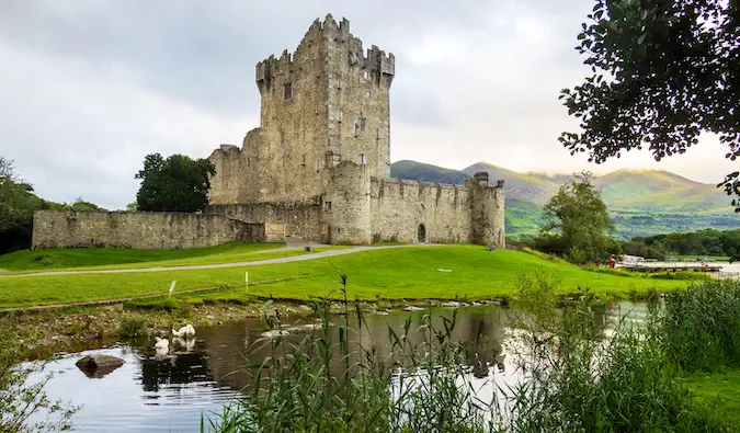 irlandzka wieża zamkowa na spokojnym jeziorze na tle zielonych wzgórz