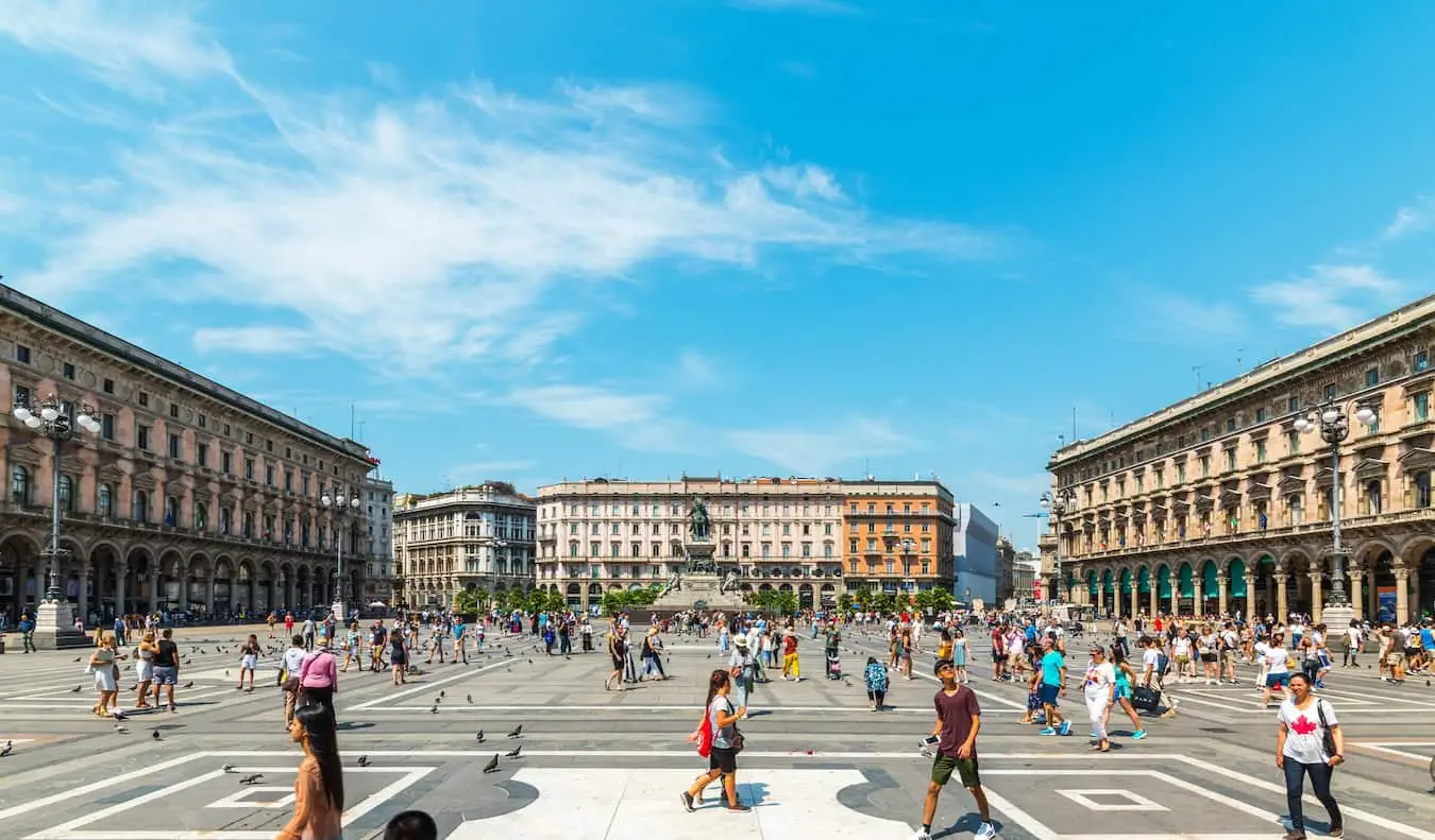 Persone che passeggiano intorno a un'enorme piazza aperta nel quartiere Centro Storico della soleggiata Milano, Italia