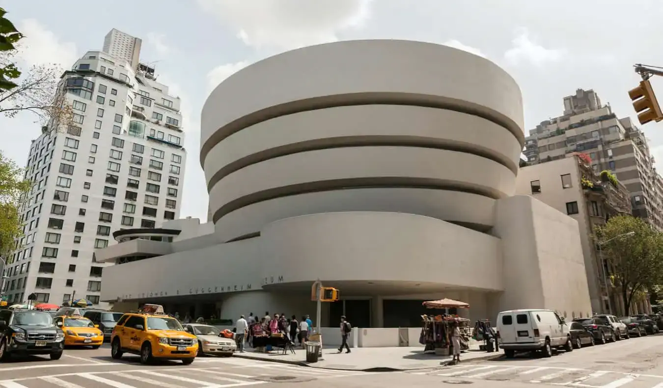 Moderní kulatý exteriér Guggenheimova muzea s taxíky projíždějícími v NYC.