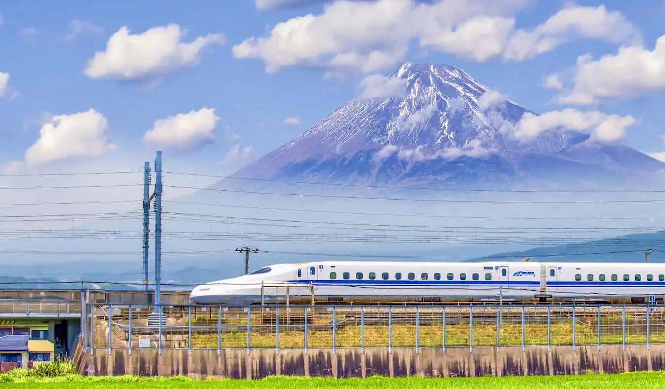 Isang bullet train na dumadaan sa magandang Mount Fuji sa Japan sa isang maaraw na araw