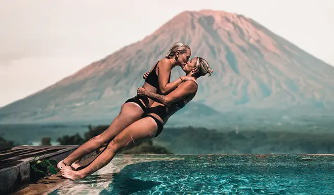 Charlotte und Natalie tauchen in einen Pool vor einem Vulkan auf Bali