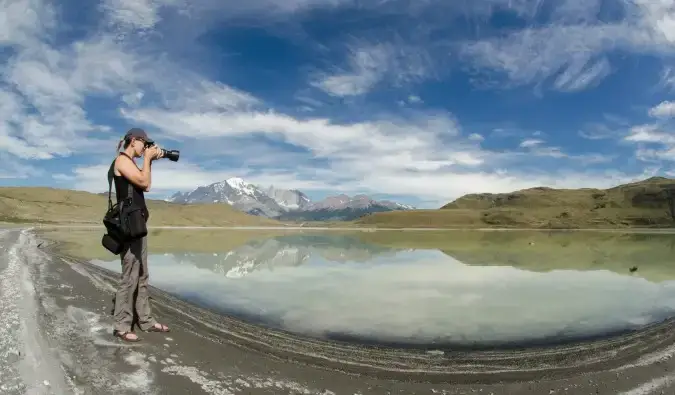 Doğada duran bir kadın profesyonel bir kamerayla fotoğraf çekiyor