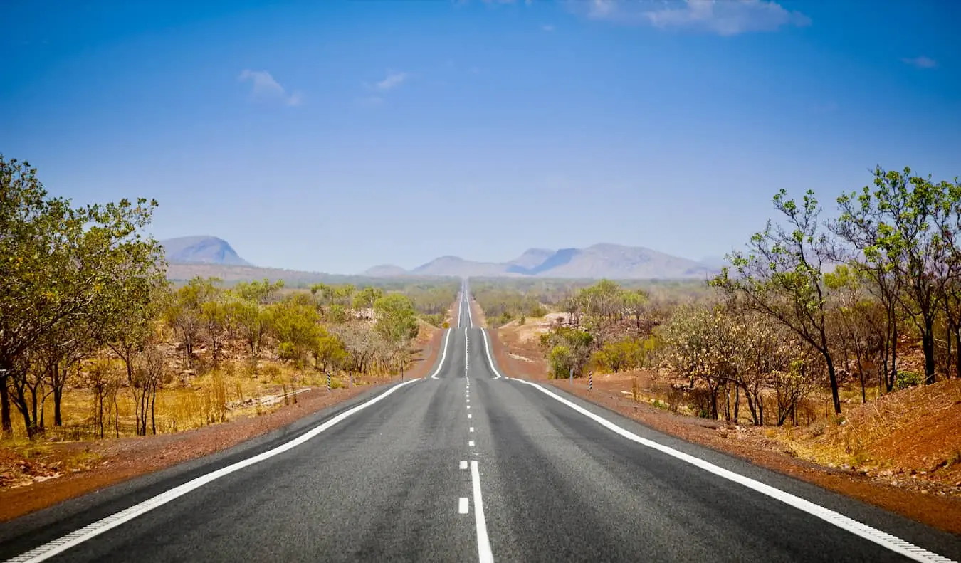 Een wijd open weg in de Outback van Australië op een heldere en zonnige dag