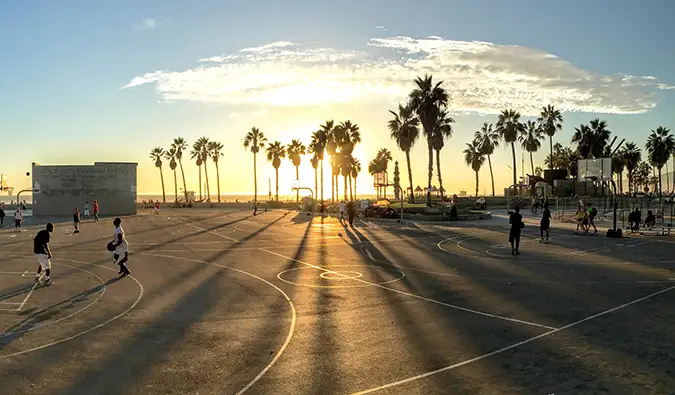 Lidé hrají basketbal v Los Angeles při západu slunce