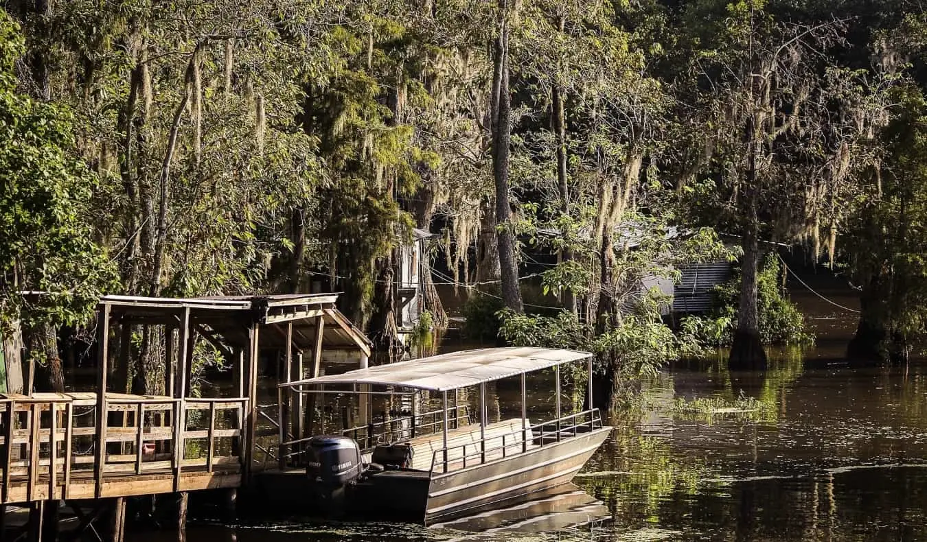 Loď před bažinami a španělskými mechem porostlými stromy v Bayou, New Orleans, Louisiana, USA