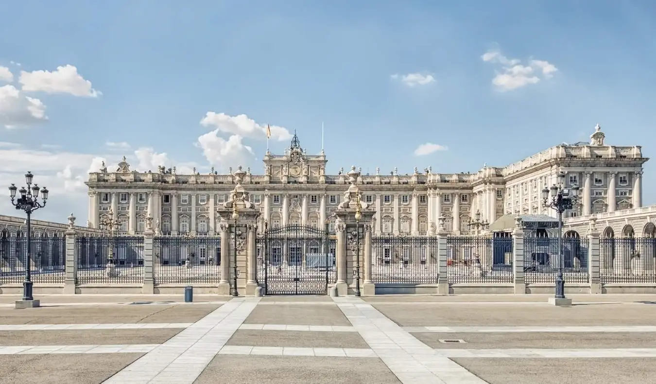 Die Steinfassade des Königspalastes mit Pinien davor in Madrid, Spanien