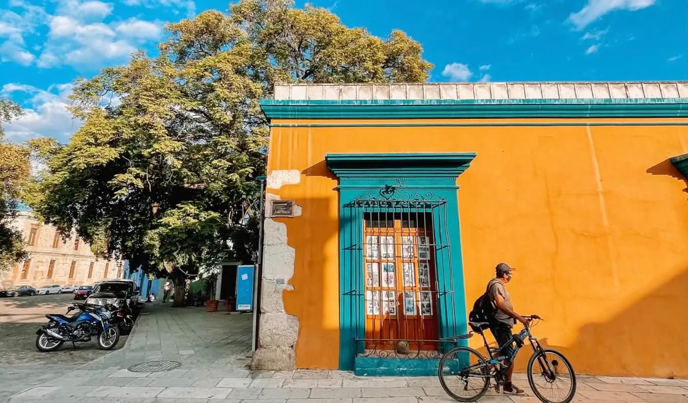 Een lokale man in Oaxaca, Mexico met een fiets bij een kleurrijk gebouw