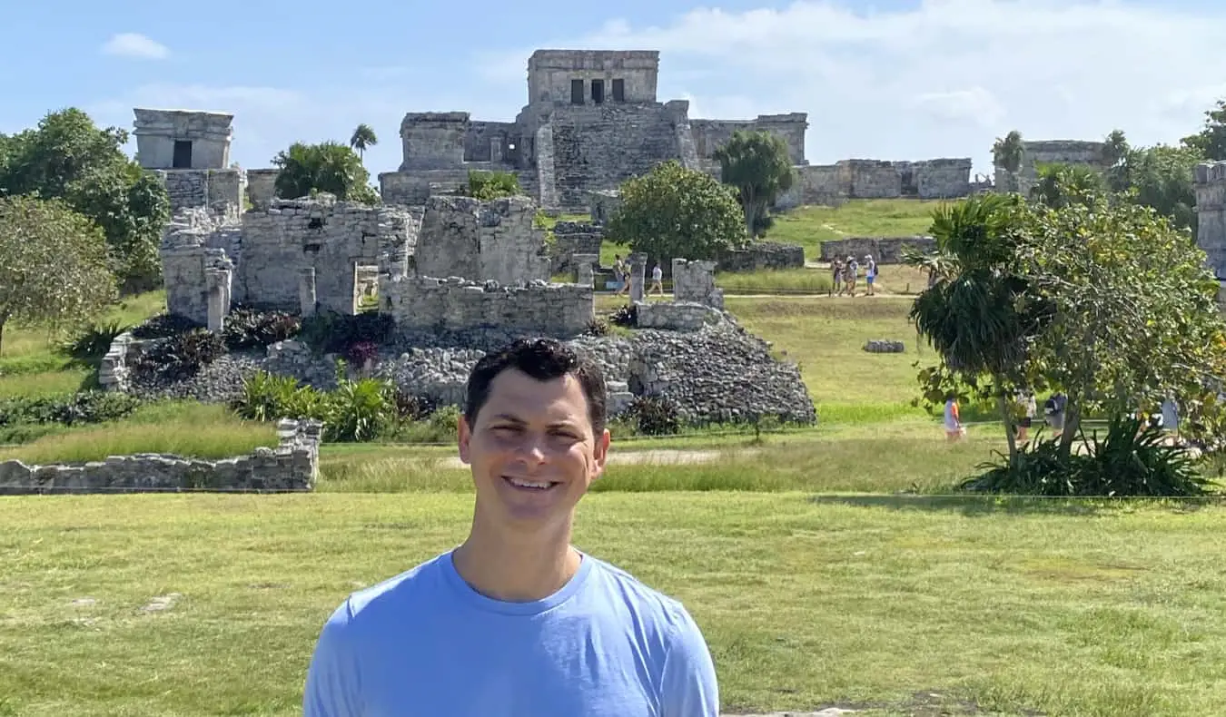 Nomadic Matt ποζάρει κοντά στα ιστορικά ερείπια του Tulum, Μεξικό