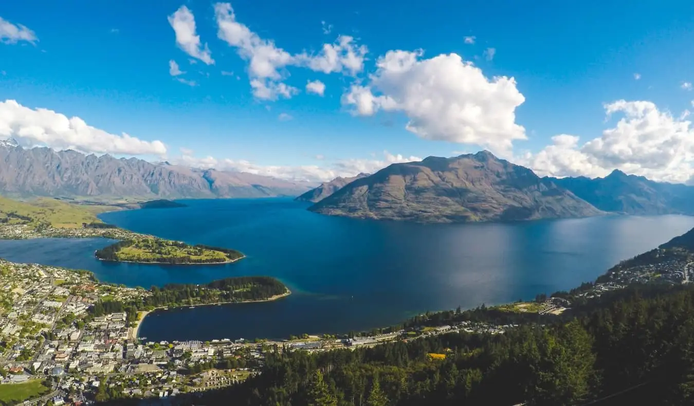 Vista aérea de Queenstown, Nova Zelândia, mostrando a cidade na água com montanhas ao fundo