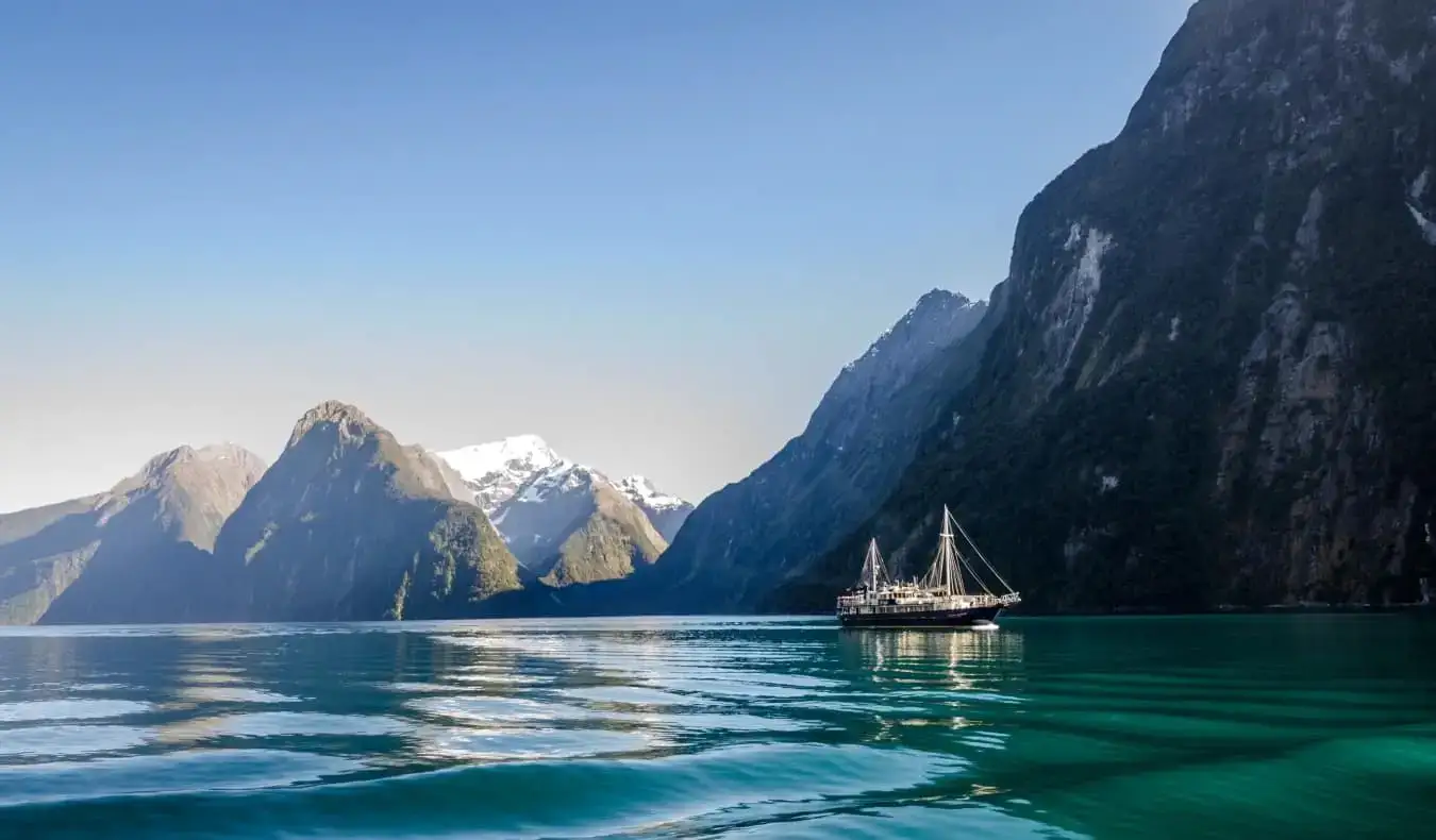 Ein Schiff vor den steilen Klippen des Milford Sound in Neuseeland