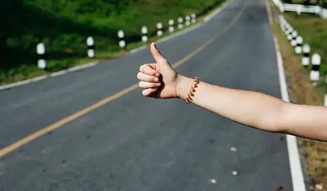 Isang hitchhiker sa isang berdeng kalsada