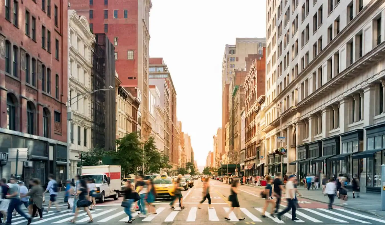 Oameni care traversează o stradă aglomerată din NYC, SUA, cu mașini de jur împrejur