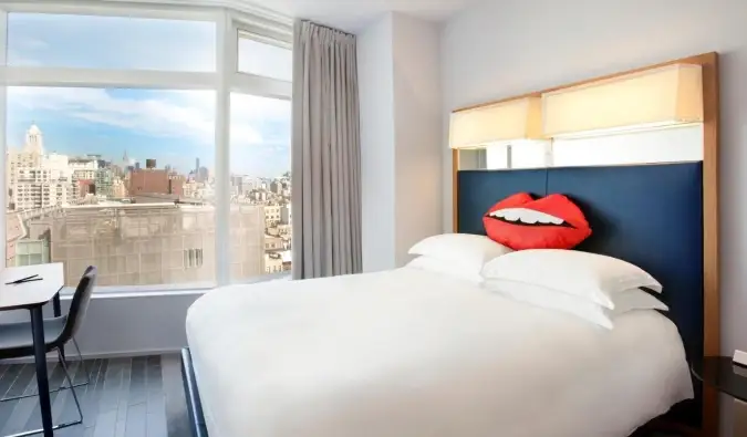 O cameră de hotel cu o pernă în formă de buze pe patul queen-size alb clar la hotelul The Standard din NYC