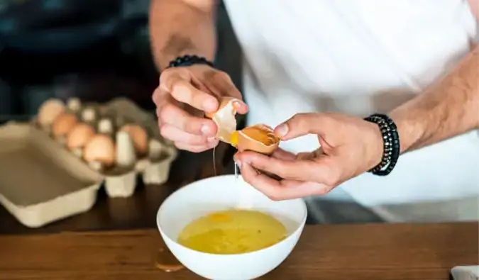 preparar el desayuno en casa rompiendo huevos en un tazón