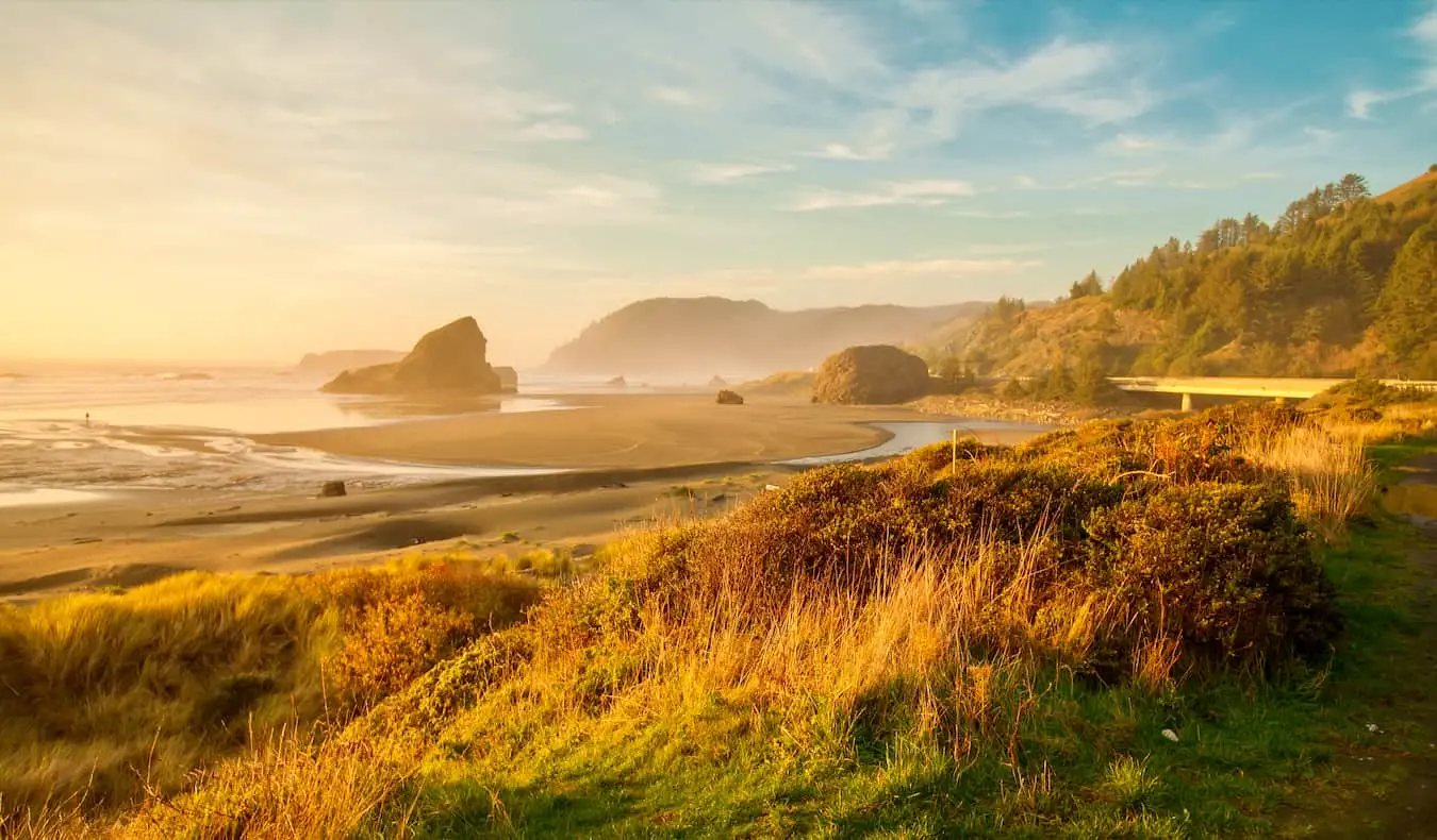 Svetel sončni vzhod nad široko, prazno plažo ob čudoviti obali Oregona