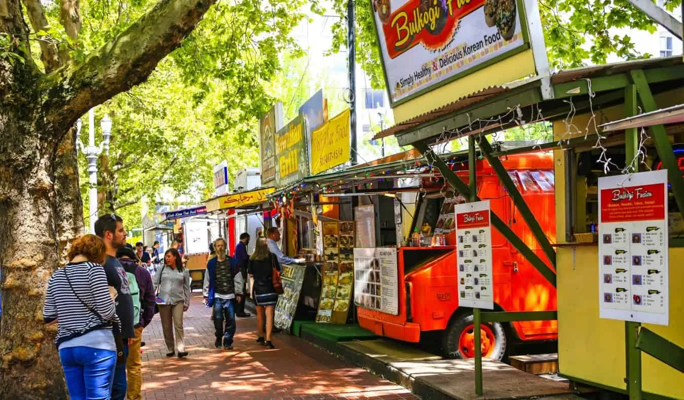 Människor som går nerför en tegeltrottoar kantad av food trucks i Portland, Oregon