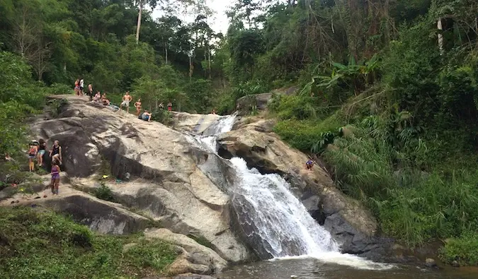 Backpacker mengunjungi salah satu dari banyak air terjun di dekat Pai, Thailand