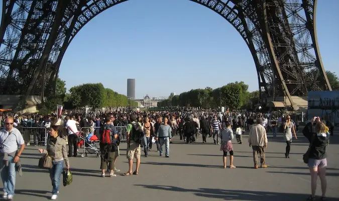 Turistas caminando debajo del exterior de la Torre Eiffel en París