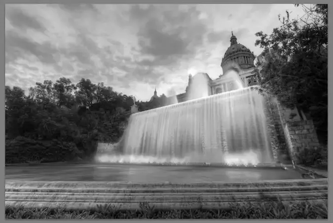 Foto eines orangefarbenen Gebäudes und Wasserfalls – Schwarzweiß – entsättigt