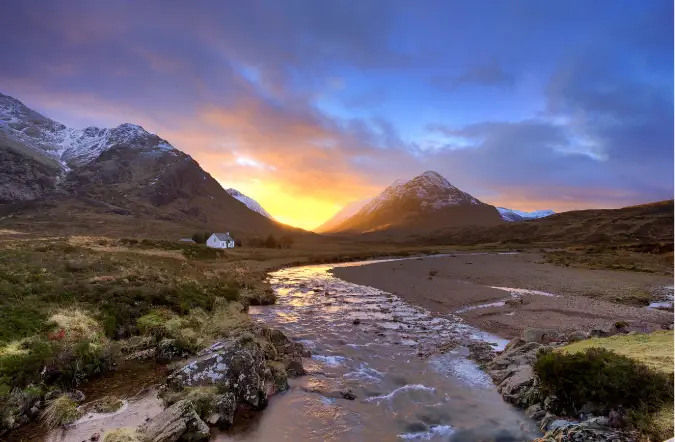 Fotografia di un fiume, di una montagna e di un tramonto colorato