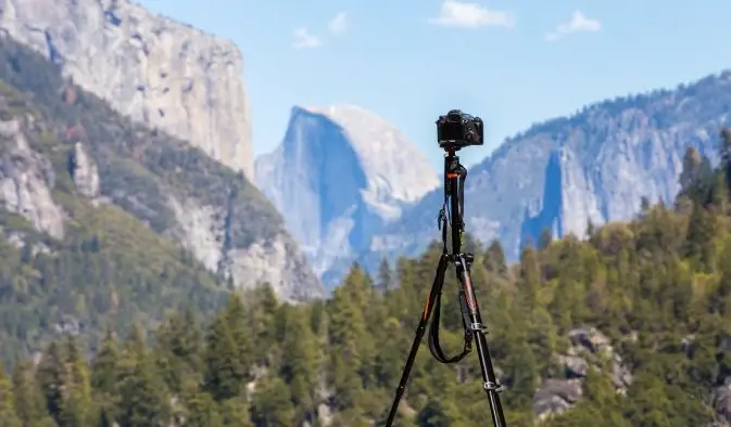 Kamera ja kolmijalka pystytetty vuoren ja luonnon edessä Yosemiten kansallispuistossa