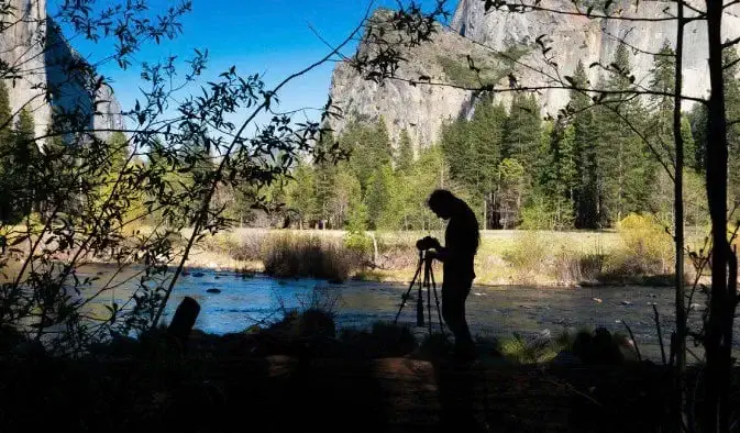 Photographe professionnel se préparant à prendre une photo de voyage nature avec un ciel bleu